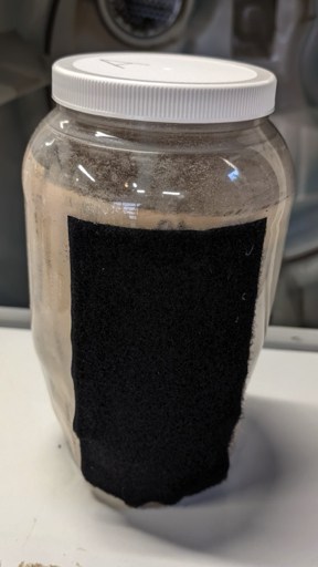 Tall plastic jar with a wide strip of black velcro glued to the side.