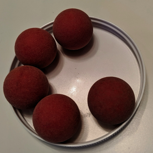 5 foosballs in a white lid. The foosballs are slightly dirty and have a reddish brown color.